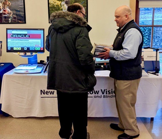 Image of Scott Krug speaking to an interested client at booth at the CCB Technology Fair on November 20, 2018