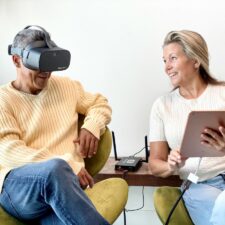 Couple looking at tablet with one person wearing Vision Buddy Low Vision Glasses