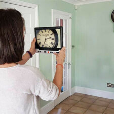 Person holding Clover 10 showing distance view of a clock on a wall
