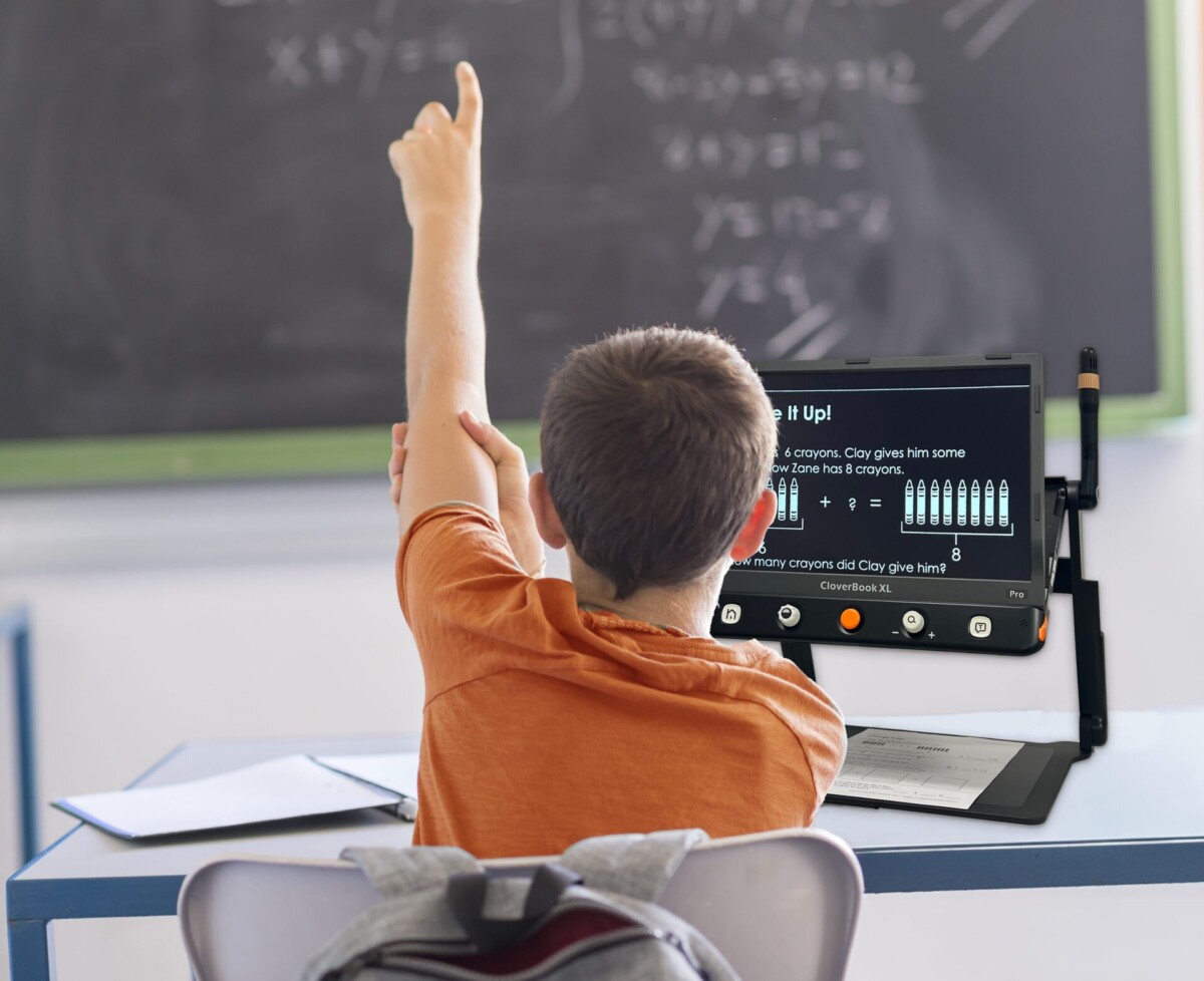 CloverBook Pro XL Desktop Magnifier on a desk in a classroom with student raising their hand