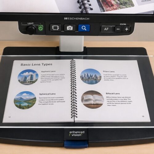 Clear plexiglass sheet placed over an open book on the reading tray of a desktop video magnifier, keeping pages flat for hands-free viewing.