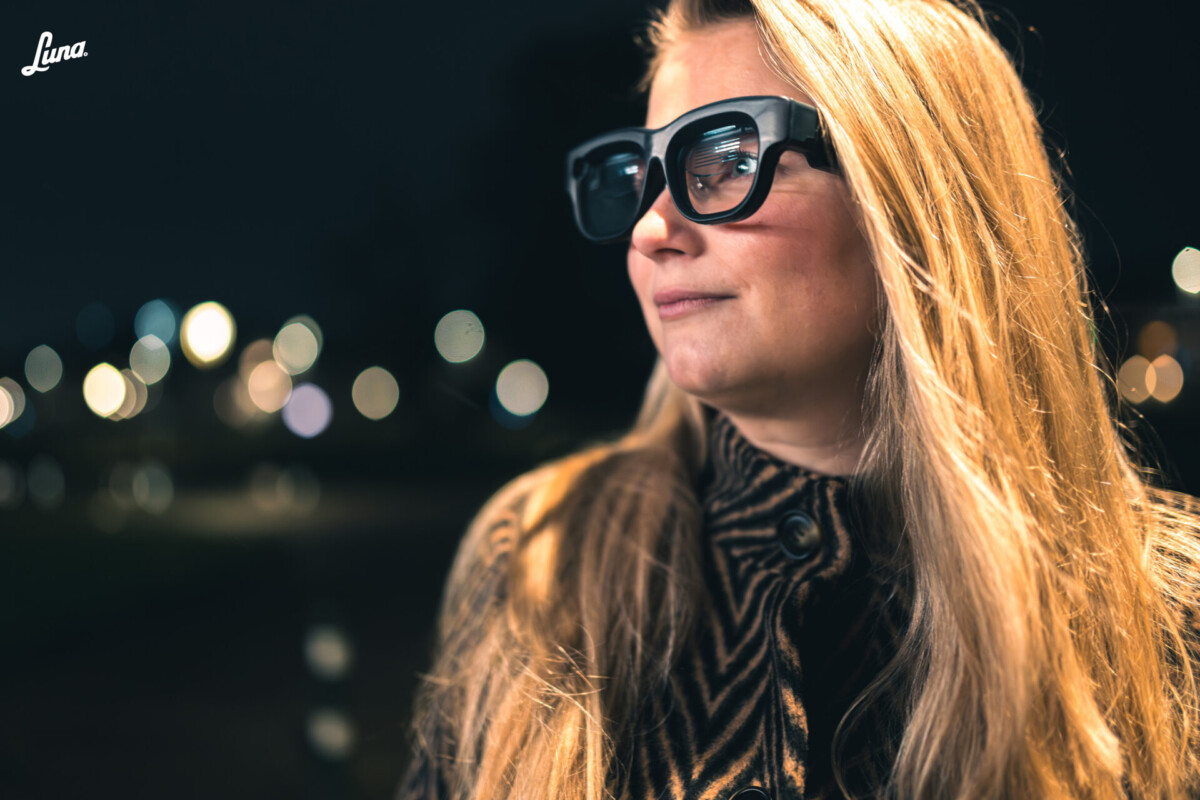 Person with long blonde hair outside at night wearing the Luna Glass