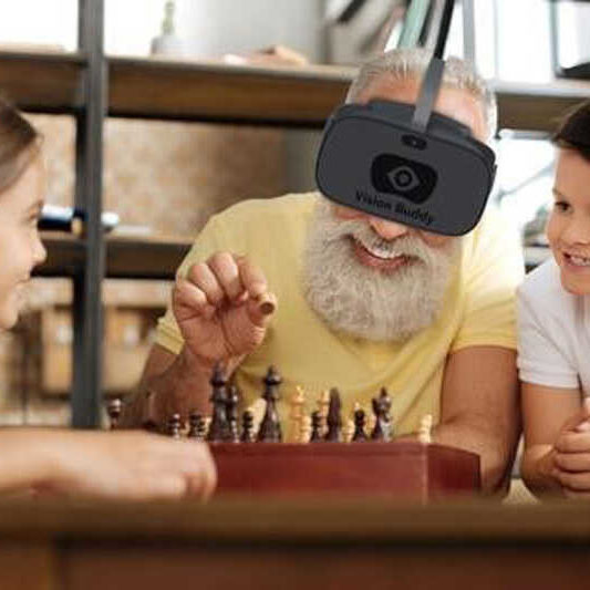 A man uses Vision Buddy Low Vision Glasses to play chess with his grandchildren
